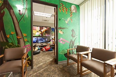 Children on bean bag chairs enjoying the TVs and Games in the waiting room