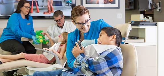 Dental hygeinist talking with a younger male patient and making him laugh