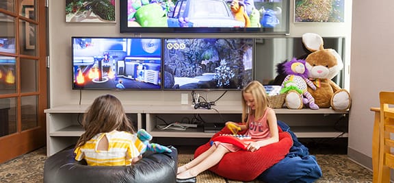 Two children enjoying the games and TVs in the waiting area