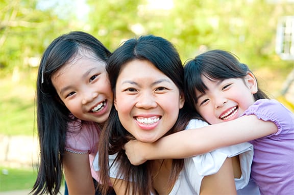Mother smiling and being hugged by her two daughters