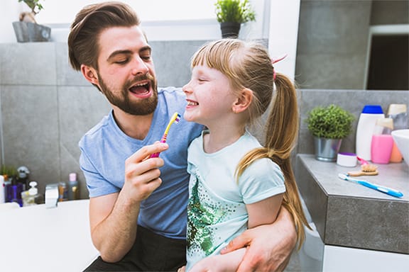 Father and daughter brushing teeth in the bathroom