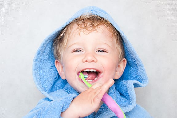 Toddler in towel brushing their teeth